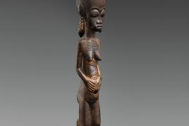 A BAULE FIGURE  Ivory Coast  The standing female with hands on the abdomen, the coiffure with tall top knot and three plaits, keloids on face, neck and body, on circular base, dark glossy patina.  43 cm. high Provenienz  Christie’s London, 7 July 1982, lot 19.  Schätzpreis: €15.000 - €20.000, Ergebnis: 40.000