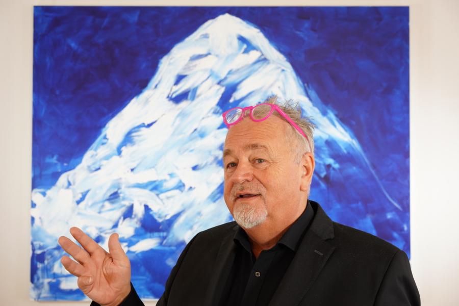 Veranstalter Helmut Reinisch vor einem Bild von Herbert Brando © Galerie Reinisch