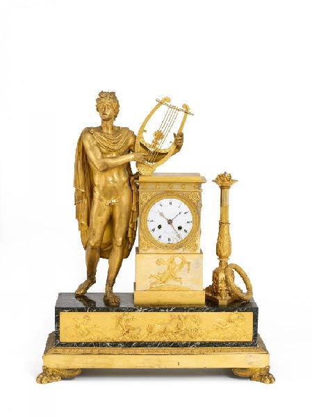 Monumentale Pendule Apoll Paris. Um 1800-07. Ferdinand Berthoud. Das Modell wohl nach einem Entwurf von Pierre-Philippe Thomire. Grau-grüner Marmor. Vergoldete Bronze. Emailzifferblatt. Rechteckiger, abgesetzter Sockel mit Palmettenfries auf Klauenfüßen ruhend. Fries mit Darstellung eines Streitwagens. Ergebnis € 22.500