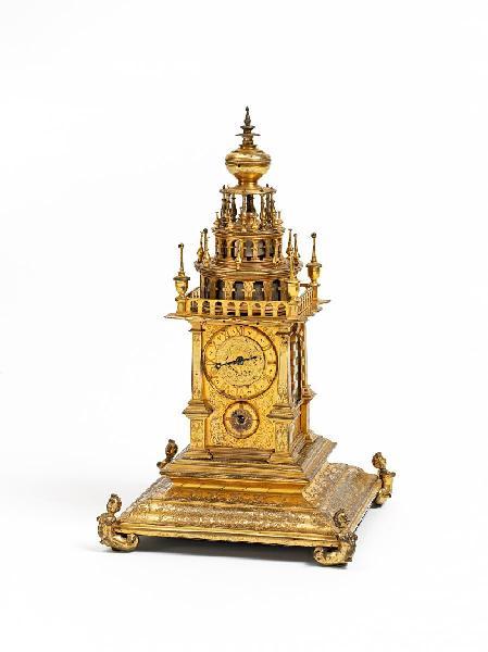 Renaissance Türmchenuhr Süddeutsch. 1. Viertel 17.Jh. Kupfer vergoldet. Quadratischer Sockel mit gekehlten Profilen, an den Ecken auf Meeresweibchen ruhend. Die Wandung mit Rankenwerk, in Reserven Musikant sowie Tiere.  Ergebnis € 32.500