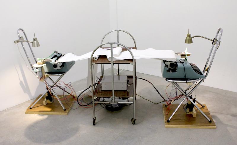 Ian Burns Debate 2014, Typewriters, chairs, table, paper, motors, timing system, 32 x 73 x 27 in. Presented by HilgerBROTKunsthalle, Vienna