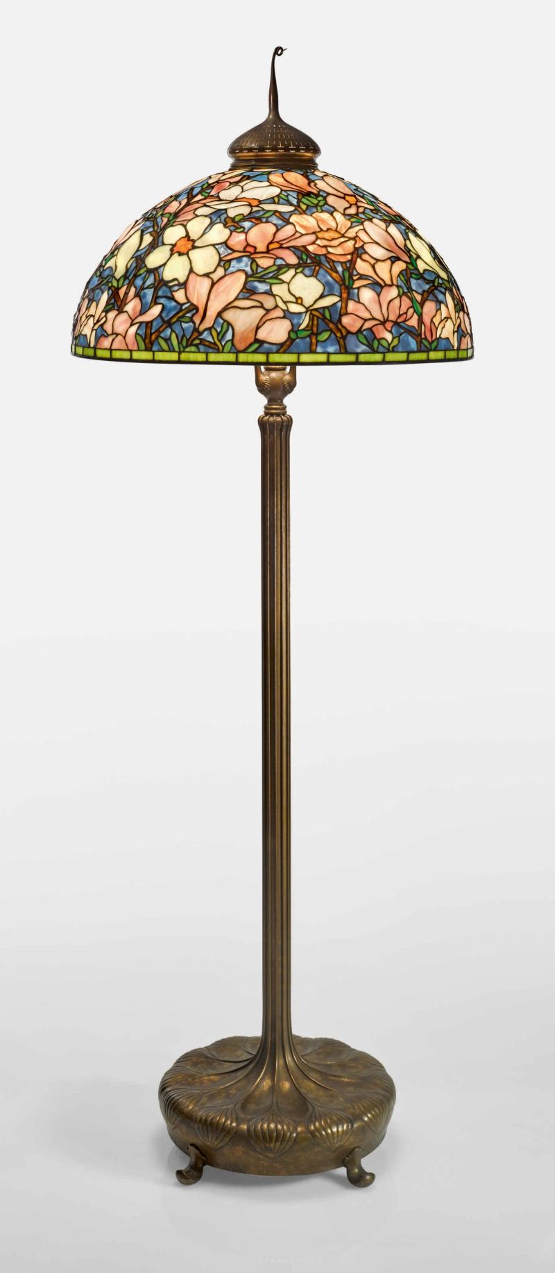 Lot 334 Tiffany Studios “Magnolia” Floor Lamp with a "Chased Pod" Senior floor lamp base and a "Pig Tail" finial shade impressed TIFFANY STVDIOS N.Y. 1599 leaded glass and gilt bronze 79 in. (200.7 cm) high 28 1/8  in. (71.4 cm) diameter of shade  circa 1920 Estimate $400/600,000