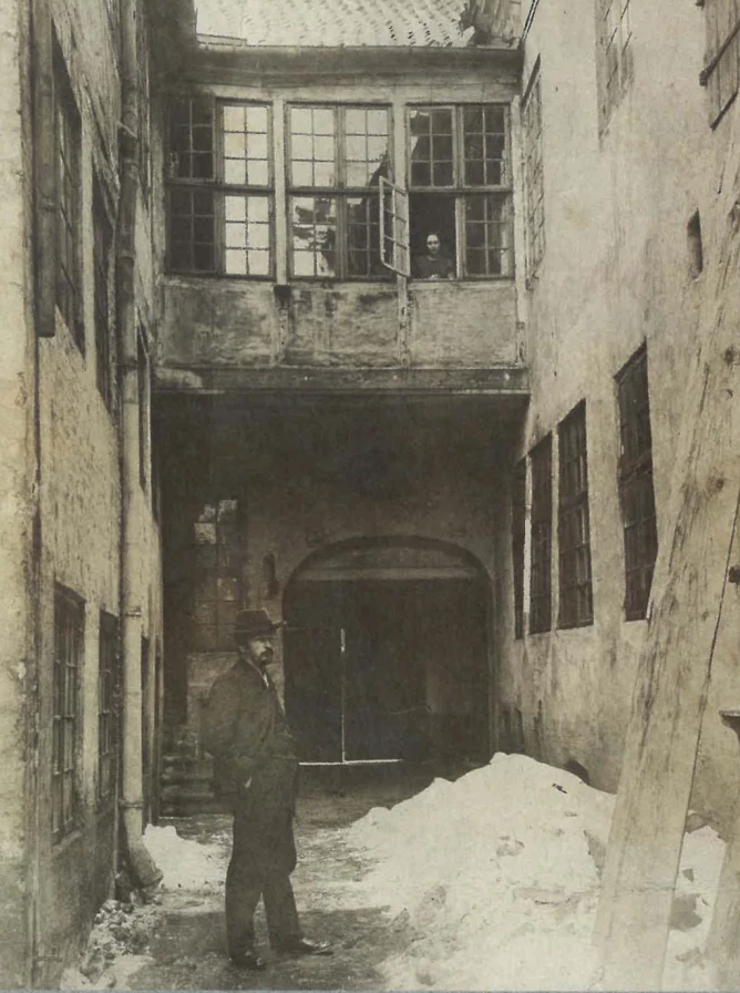 Vilhelm Hammershøi in the courtyard outside Strandgade 30, with his wife Ida at the window